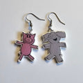 Piggy and Elephant dangle silver dangle earrings made out of polymer clay on a white background. 