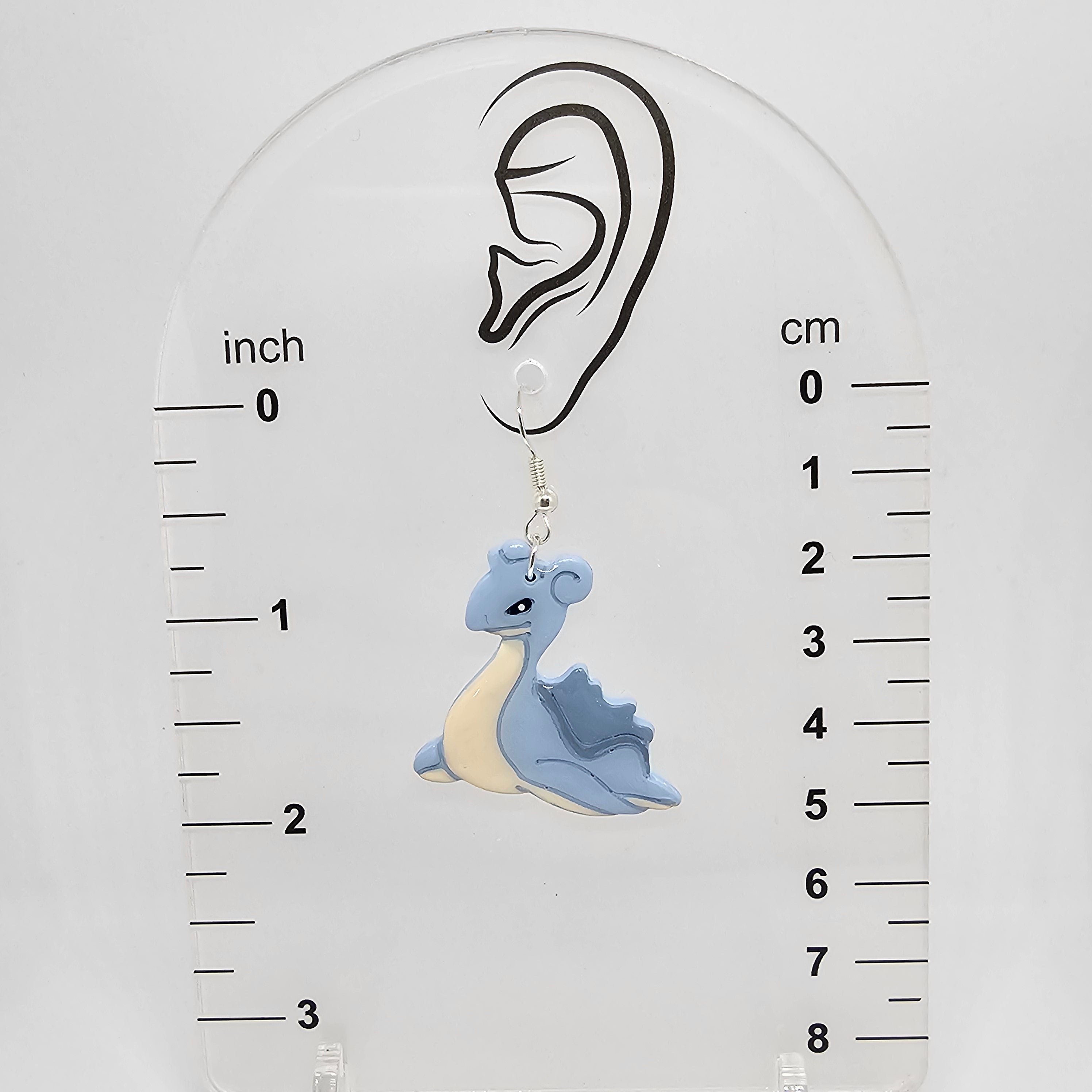 Dangle lapras earrings on a measuring device showing the earrings hang 2in from ear lobe hole. 