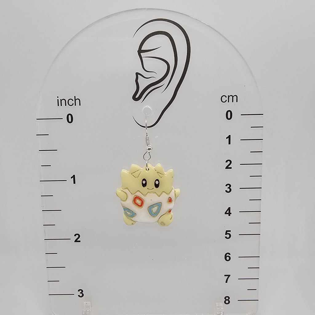 Togepi dangle earrings on a measuring device showing the earrings hang 1.75in from the ear lobe hole. 