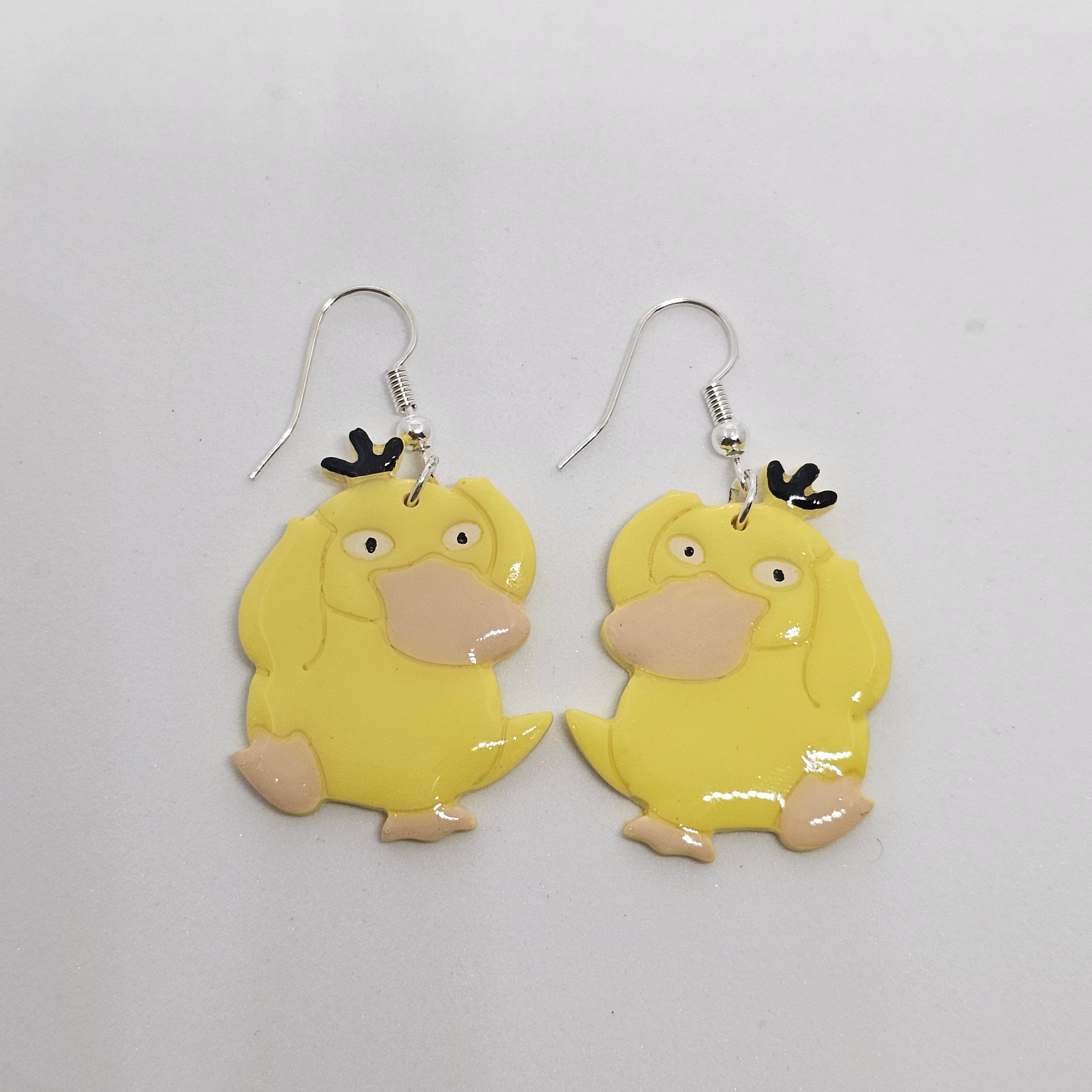 White gold dangle earrings with the Pokemon Psyduck made out of polymer clay