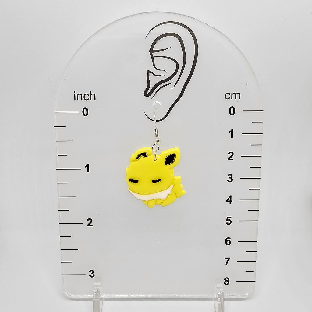 Jolteon earring on a measuring device showing it dangles 1.75in below the earring lobe hole.