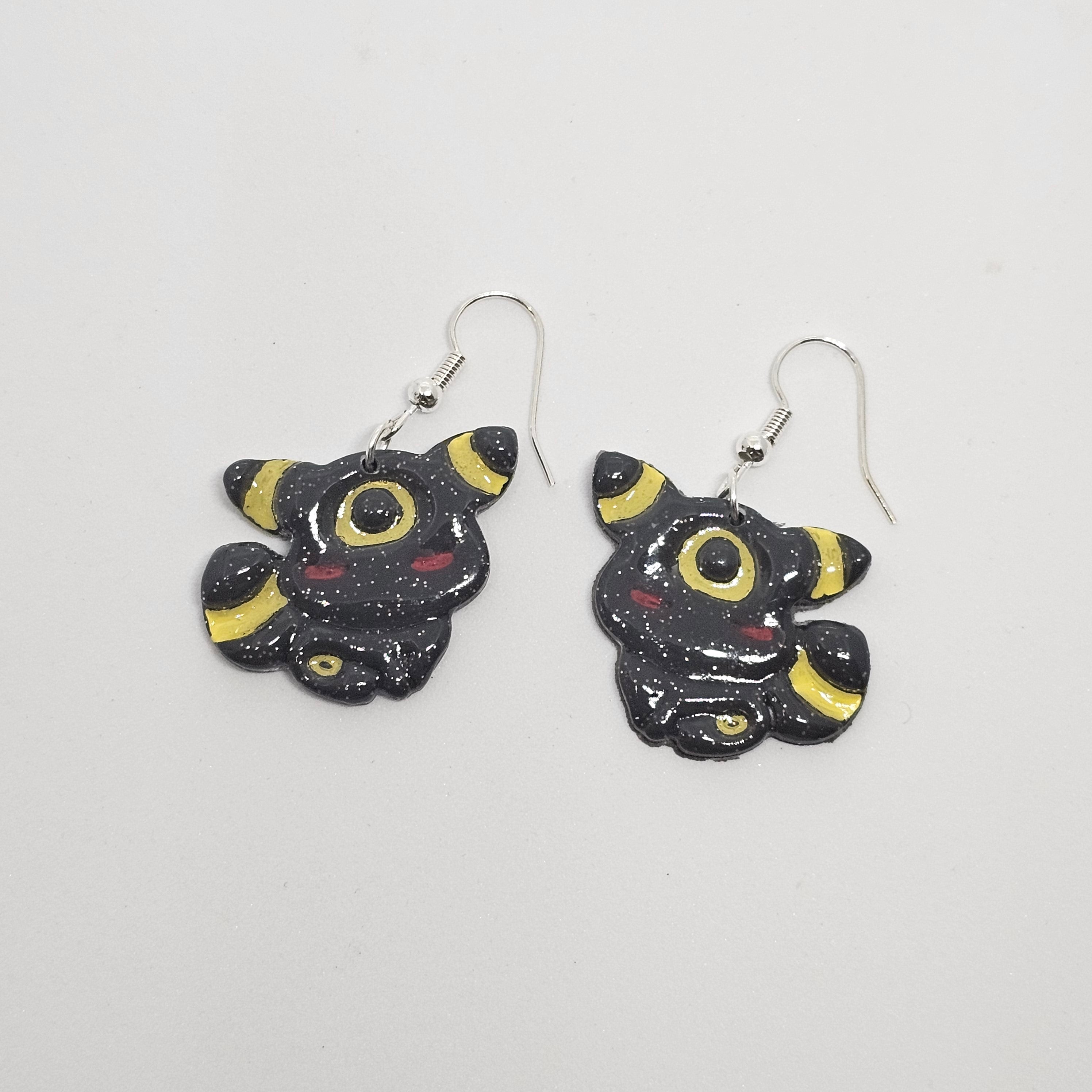 White gold dangle earrings of Pokemon Umbreon made out of polymer clay.